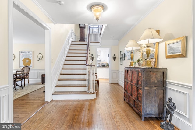 entryway with ornamental molding and light hardwood / wood-style flooring