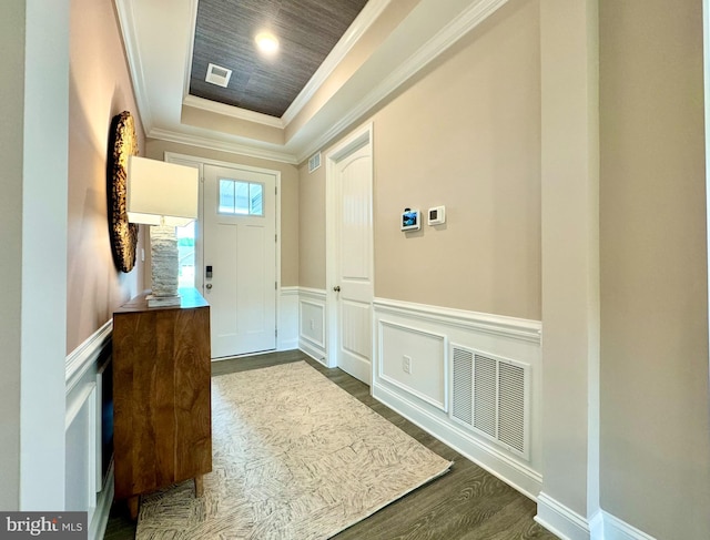 foyer entrance featuring ornamental molding, a raised ceiling, and dark wood-type flooring