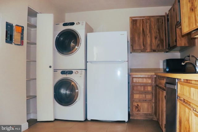 clothes washing area with stacked washer / dryer, sink, and light tile patterned floors