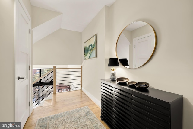 corridor with vaulted ceiling and light hardwood / wood-style floors