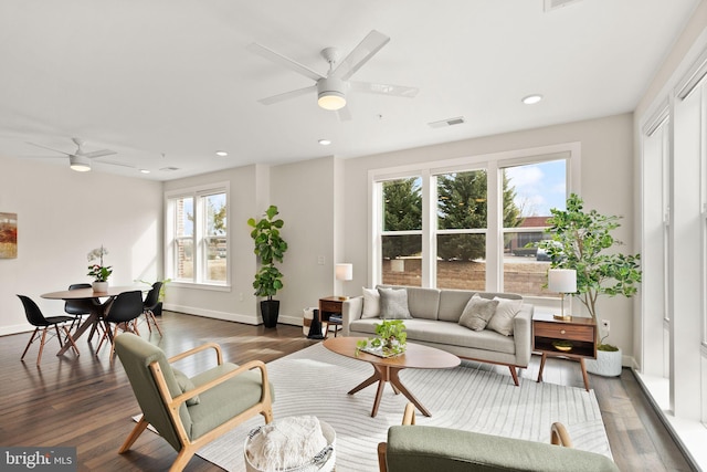 living room featuring ceiling fan and dark wood-type flooring