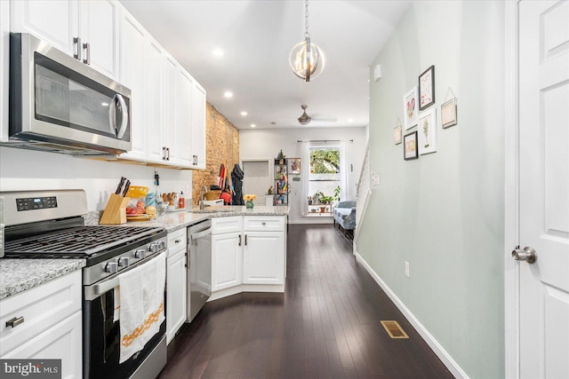 kitchen featuring stainless steel appliances, white cabinetry, light stone counters, dark hardwood / wood-style floors, and pendant lighting