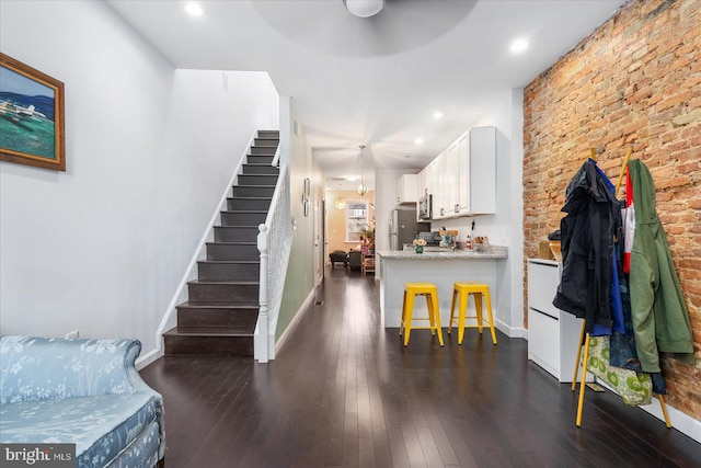 interior space with appliances with stainless steel finishes, light stone counters, dark hardwood / wood-style floors, a breakfast bar area, and white cabinets