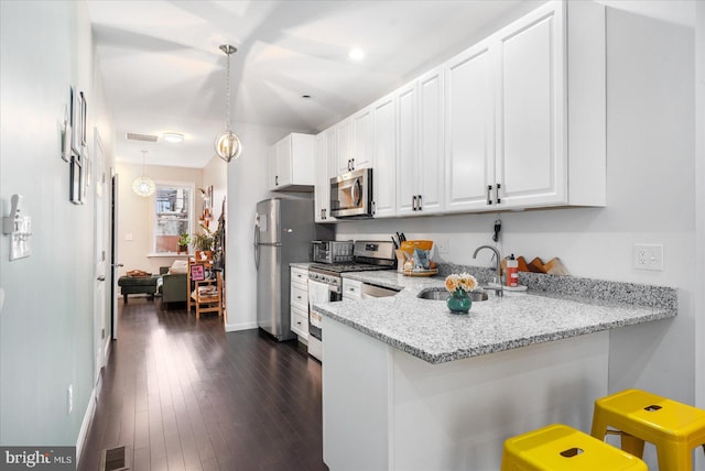 kitchen with stainless steel appliances, white cabinetry, light stone countertops, hanging light fixtures, and a breakfast bar area