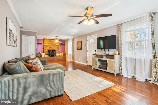 living room with a large fireplace, a textured ceiling, hardwood / wood-style floors, ceiling fan, and ornamental molding