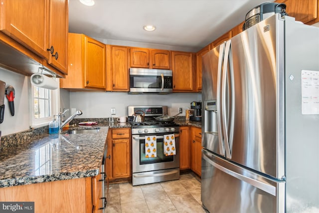 kitchen featuring sink, appliances with stainless steel finishes, light tile patterned floors, and dark stone counters