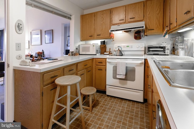 kitchen with kitchen peninsula, a kitchen breakfast bar, white appliances, and sink