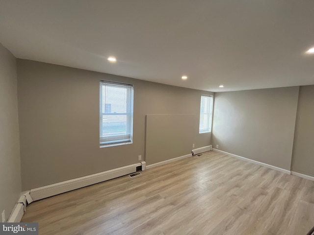 unfurnished room with a baseboard heating unit and light hardwood / wood-style floors