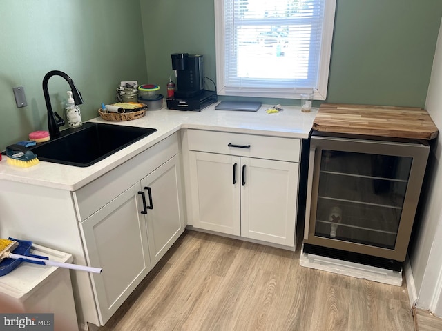 kitchen featuring light hardwood / wood-style flooring, white cabinetry, sink, and beverage cooler