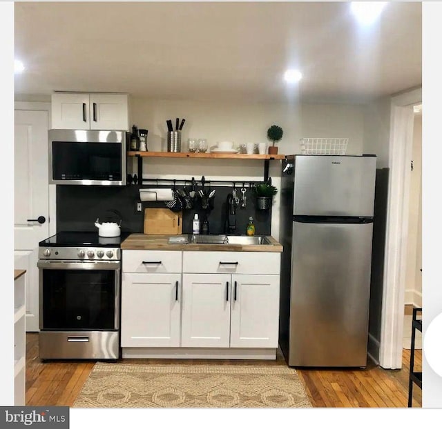 kitchen with white cabinetry, appliances with stainless steel finishes, sink, and light wood-type flooring