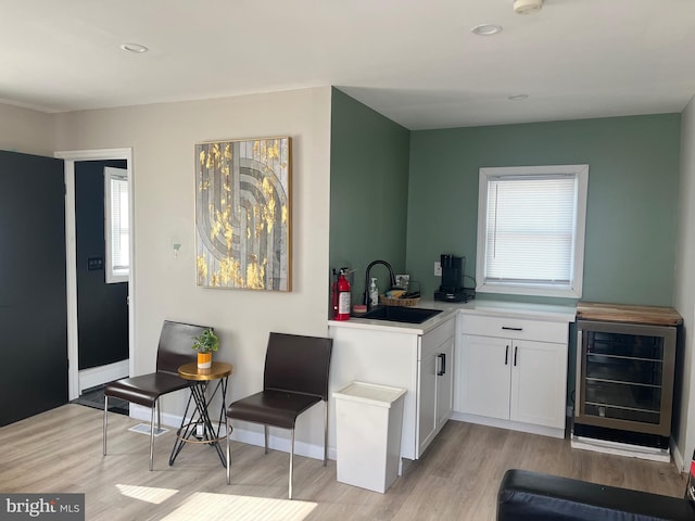 kitchen with wine cooler, sink, white cabinets, and a healthy amount of sunlight