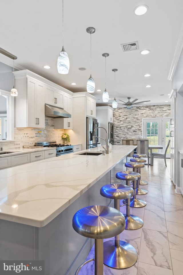 kitchen featuring sink, pendant lighting, crown molding, white cabinetry, and a breakfast bar area