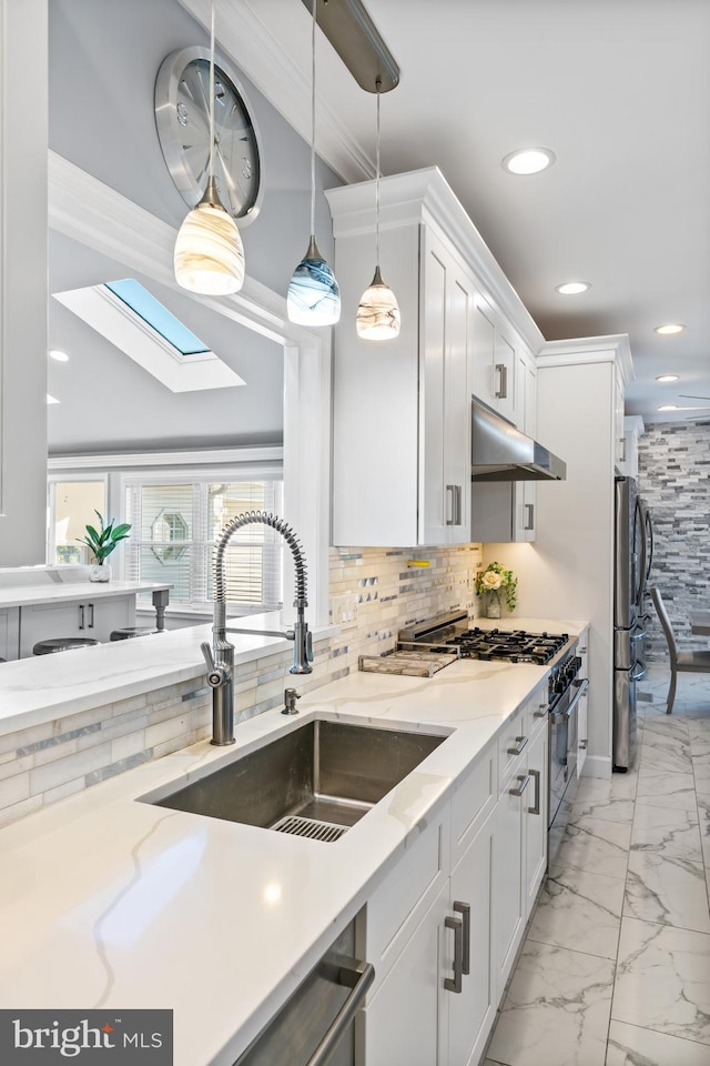 kitchen featuring a skylight, light stone counters, appliances with stainless steel finishes, and white cabinets