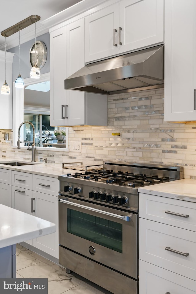 kitchen featuring decorative backsplash, sink, pendant lighting, high end range, and white cabinetry