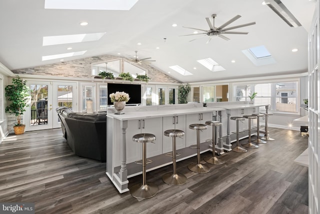 kitchen with dark wood-type flooring, a kitchen breakfast bar, vaulted ceiling, and a healthy amount of sunlight