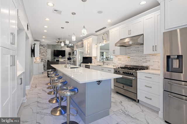 kitchen featuring pendant lighting, white cabinets, sink, stainless steel appliances, and a breakfast bar area