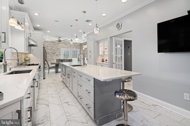 kitchen featuring a spacious island, decorative light fixtures, sink, and white cabinetry