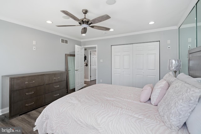 bedroom featuring dark wood-type flooring, a closet, crown molding, and ceiling fan