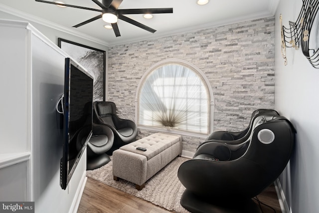 living area with ornamental molding, hardwood / wood-style flooring, and ceiling fan