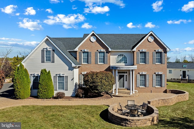 colonial-style house with an outdoor fire pit and a front yard