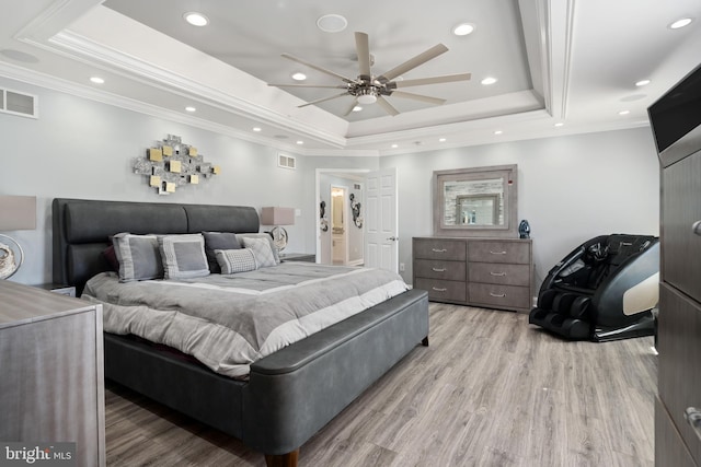 bedroom with ceiling fan, a tray ceiling, ornamental molding, and light hardwood / wood-style floors