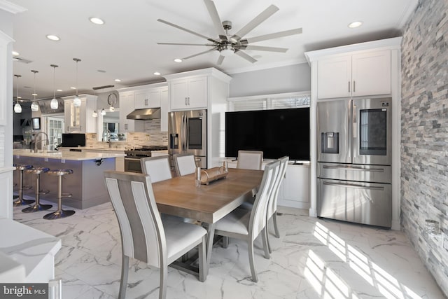 dining area featuring crown molding, sink, and ceiling fan