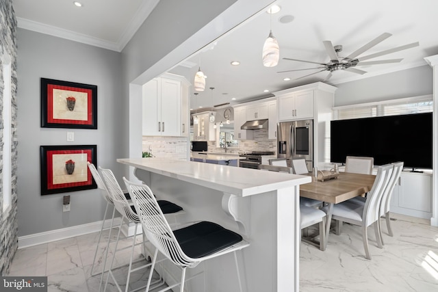 kitchen featuring decorative backsplash, stainless steel appliances, white cabinets, kitchen peninsula, and pendant lighting