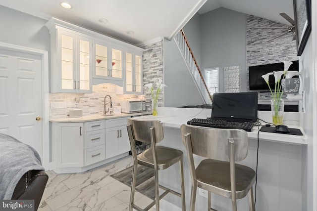 bar with backsplash, vaulted ceiling, sink, and white cabinetry