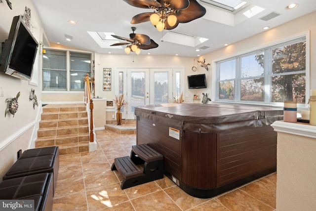 misc room with a skylight, ceiling fan, a hot tub, and light tile patterned flooring