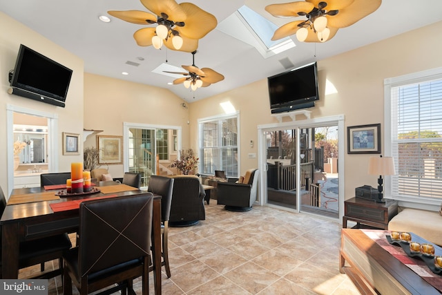 tiled dining space with ceiling fan, a wealth of natural light, and vaulted ceiling with skylight