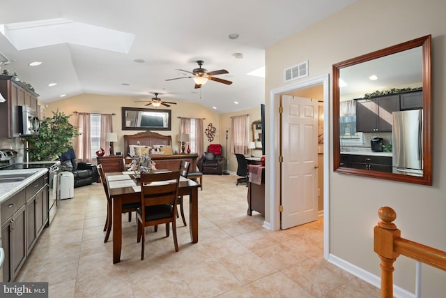 tiled dining room featuring ceiling fan and vaulted ceiling with skylight