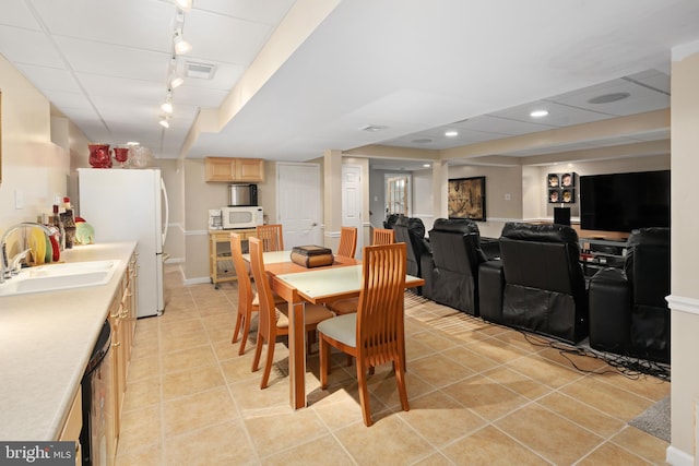 tiled dining area featuring a paneled ceiling, sink, and rail lighting