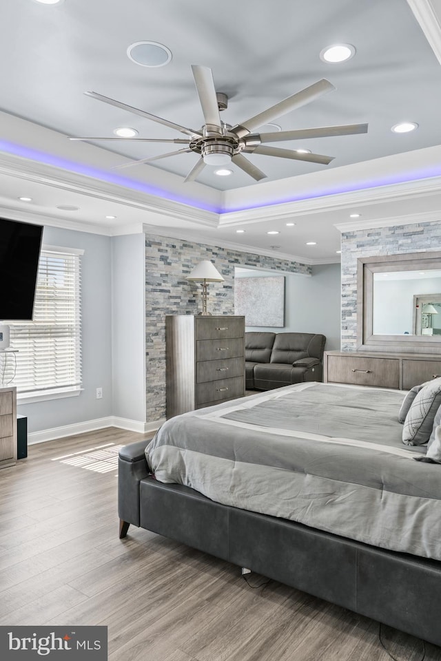 bedroom with ceiling fan, a raised ceiling, crown molding, and hardwood / wood-style floors