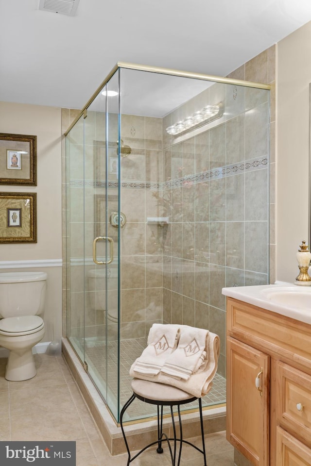 bathroom featuring vanity, tile patterned flooring, toilet, and an enclosed shower