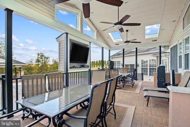 sunroom / solarium featuring ceiling fan, lofted ceiling with skylight, and a wealth of natural light