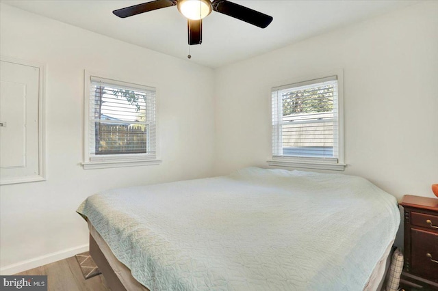 bedroom featuring light hardwood / wood-style flooring, ceiling fan, and multiple windows