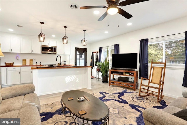 living room featuring sink, light wood-type flooring, and ceiling fan