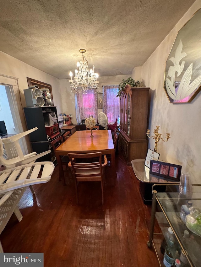 dining area with a textured ceiling, a chandelier, and dark wood-type flooring