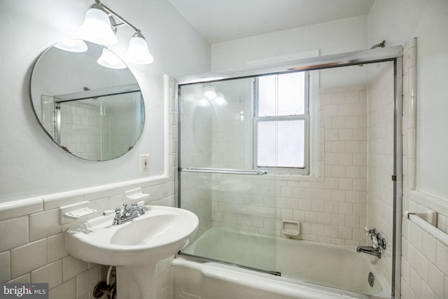 bathroom with tile walls, sink, and enclosed tub / shower combo