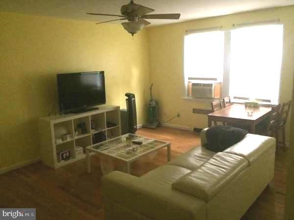 living room with cooling unit, ceiling fan, radiator, and hardwood / wood-style flooring