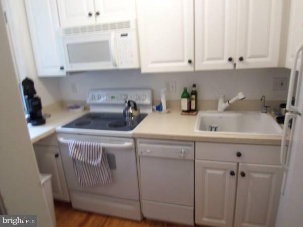 kitchen with sink, white cabinets, white appliances, and light hardwood / wood-style flooring