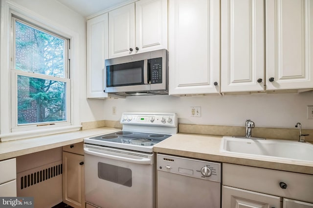 kitchen featuring white cabinetry, appliances with stainless steel finishes, radiator, and sink