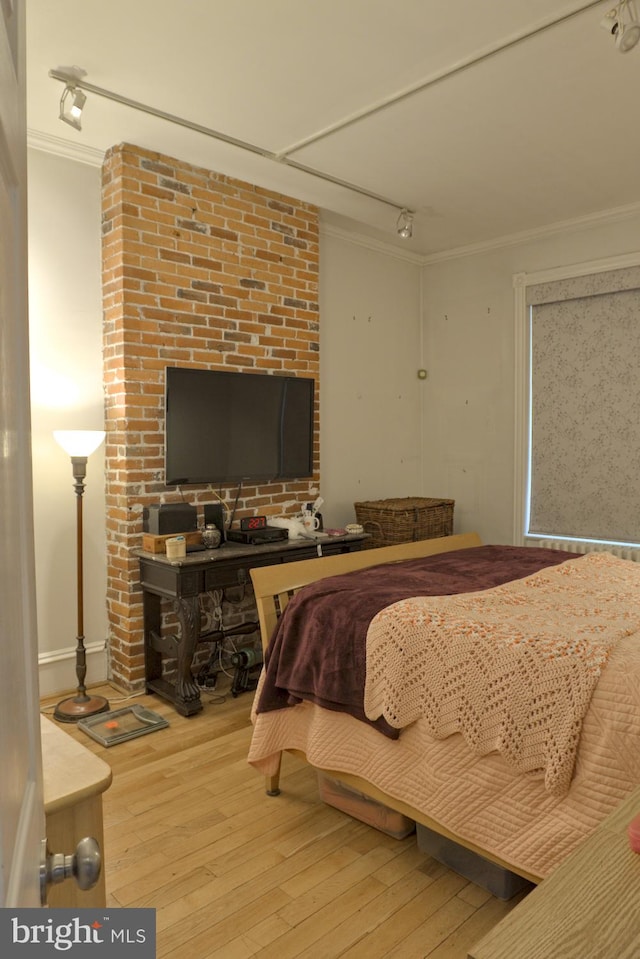 bedroom featuring track lighting, ornamental molding, and wood-type flooring