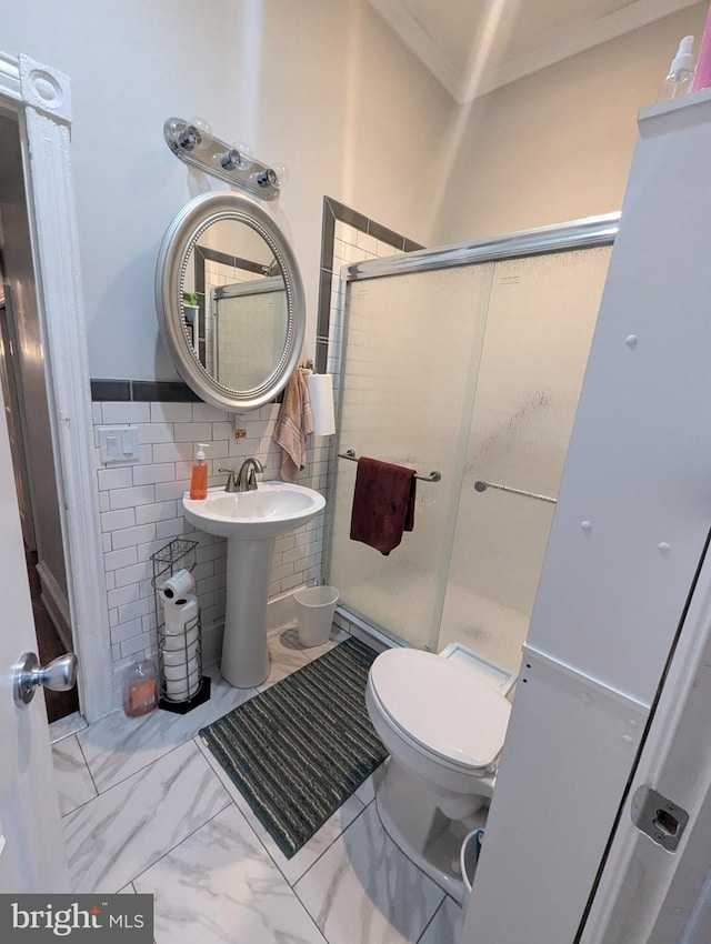 bathroom with tile walls, a shower with shower door, and toilet