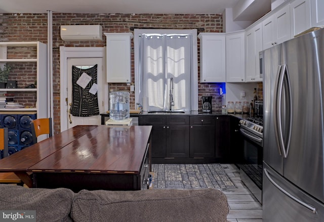 kitchen featuring brick wall, appliances with stainless steel finishes, white cabinetry, and an AC wall unit