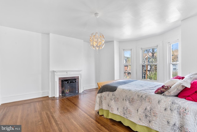 4830 Cedar Ave, Philadelphia, PA 19143 - bedroom featuring a brick fireplace, a notable chandelier, baseboards, and wood finished floors