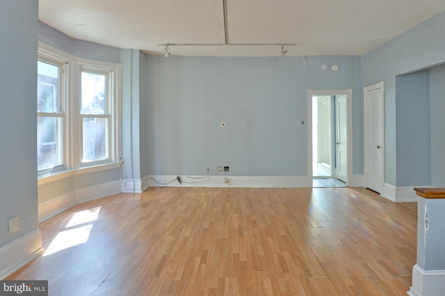 empty room with light wood-type flooring and track lighting