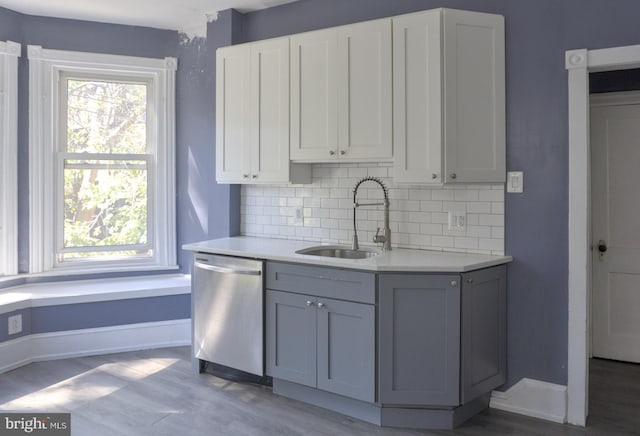 kitchen featuring sink, decorative backsplash, stainless steel dishwasher, and light hardwood / wood-style floors