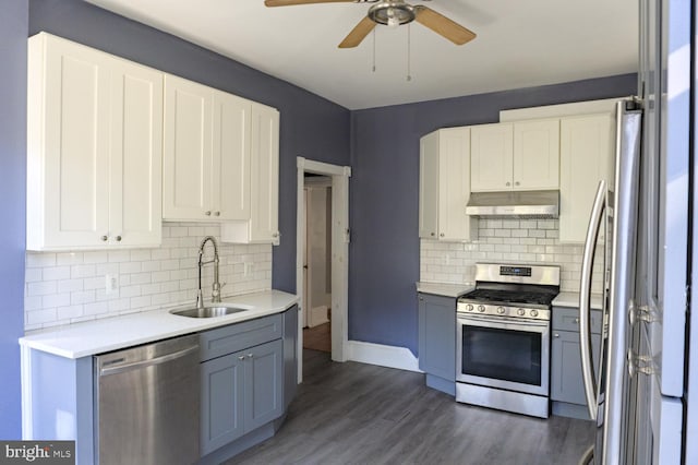 kitchen with dark hardwood / wood-style floors, stainless steel appliances, white cabinets, sink, and backsplash