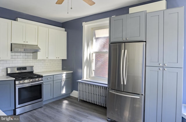 kitchen with ceiling fan, radiator, backsplash, appliances with stainless steel finishes, and hardwood / wood-style flooring